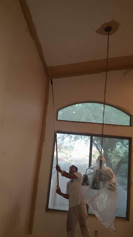 Worker hanging a large transparent plastic sheet near an arched window inside a room
