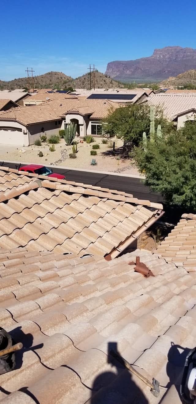 Sunlit desert neighborhood with tan tile roofs and mountains in the background