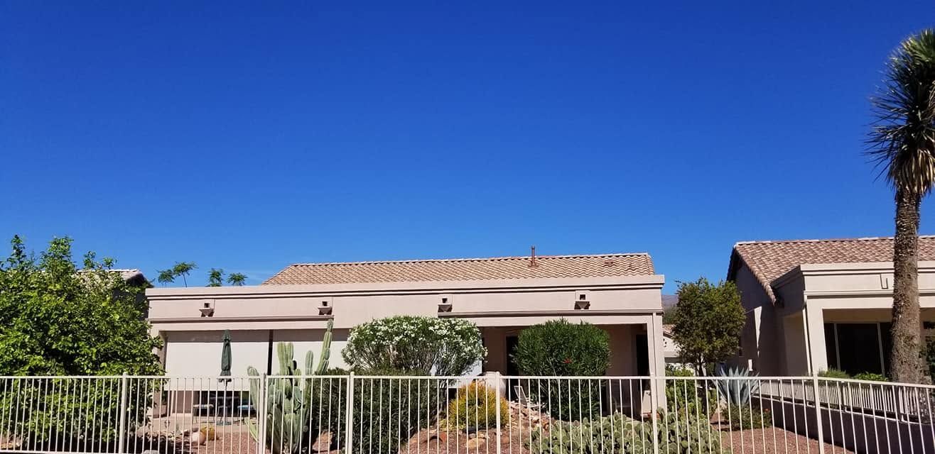 Single-story stucco houses behind a white fence under a bright blue sky