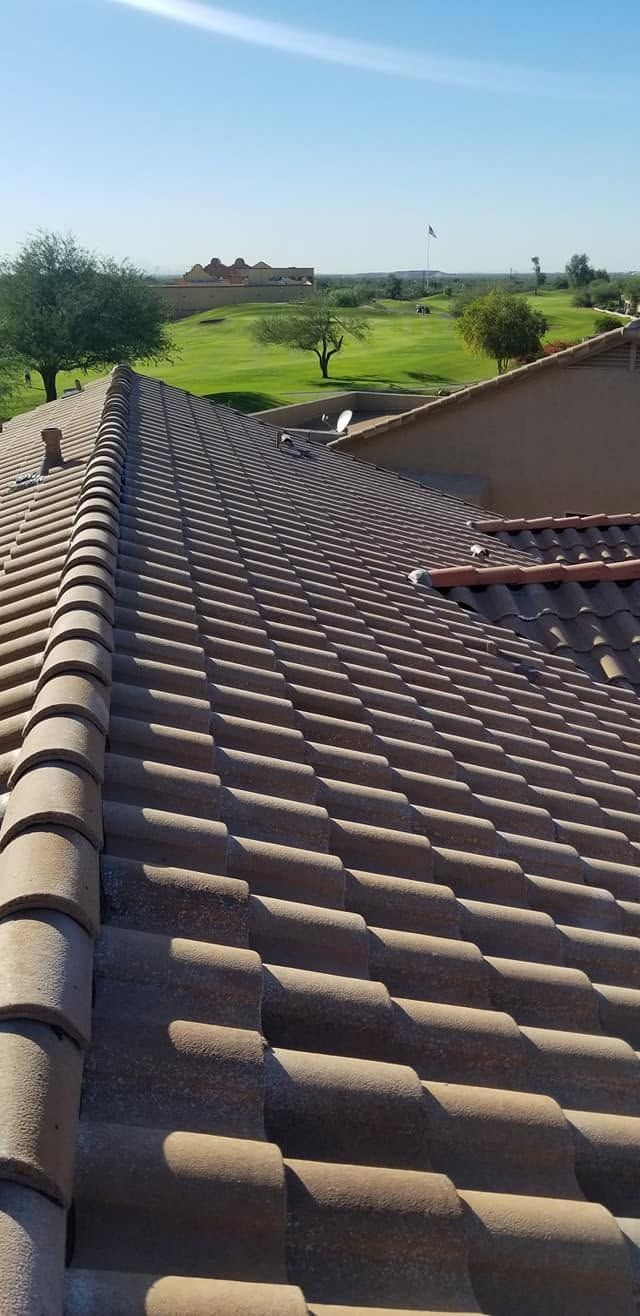 Red clay tile roof overlooking a green hillside under a clear blue sky
