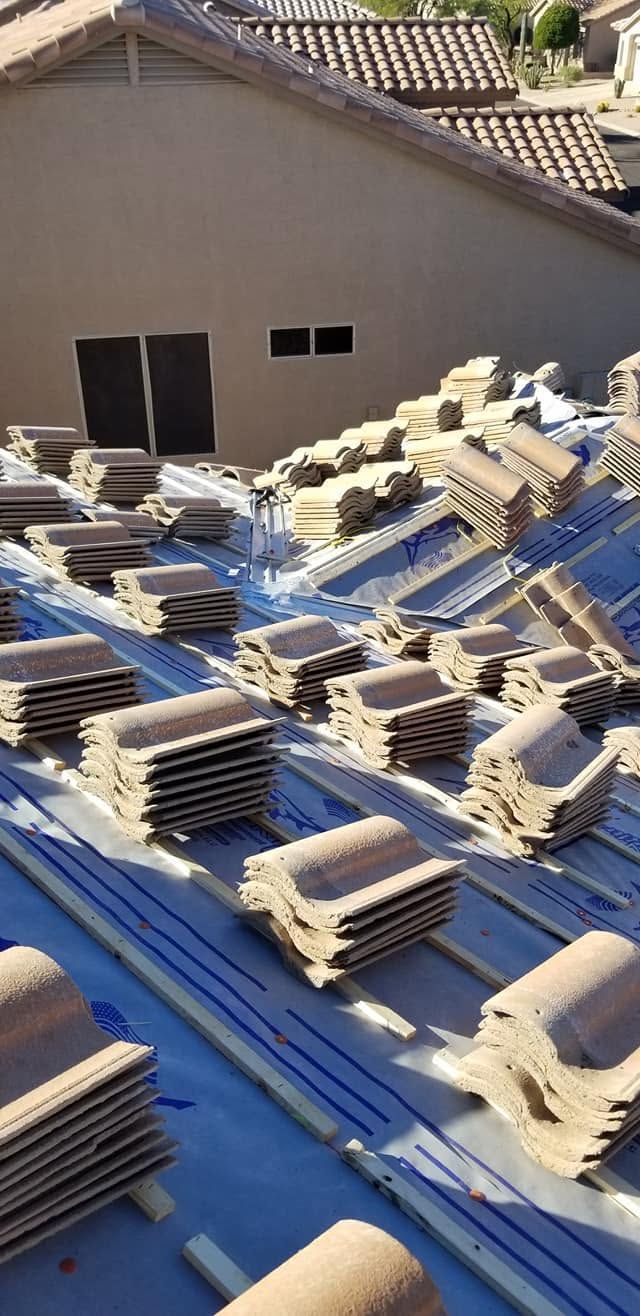 Blue tarp-covered rooftop with stacks of roof tiles and building materials