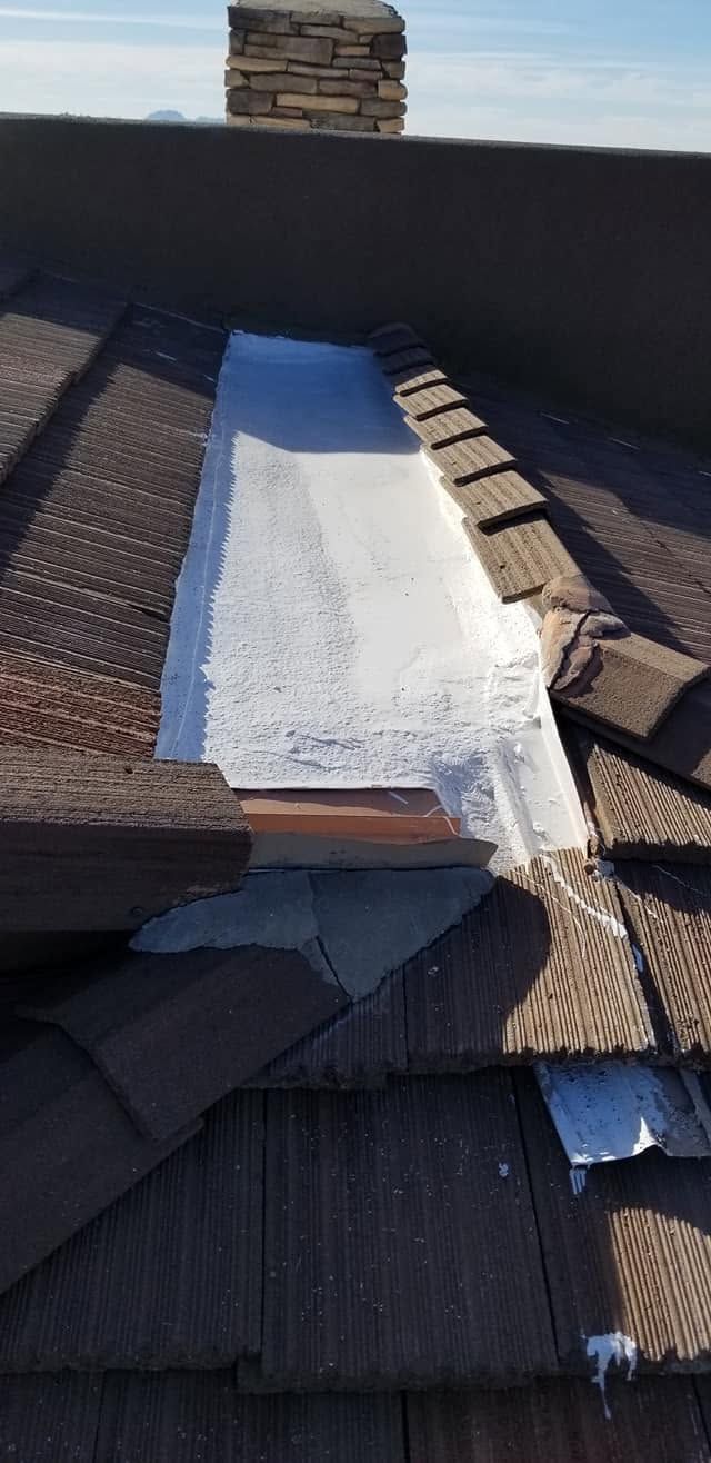 Damaged roof with a white tarp patch over missing shingles near a chimney