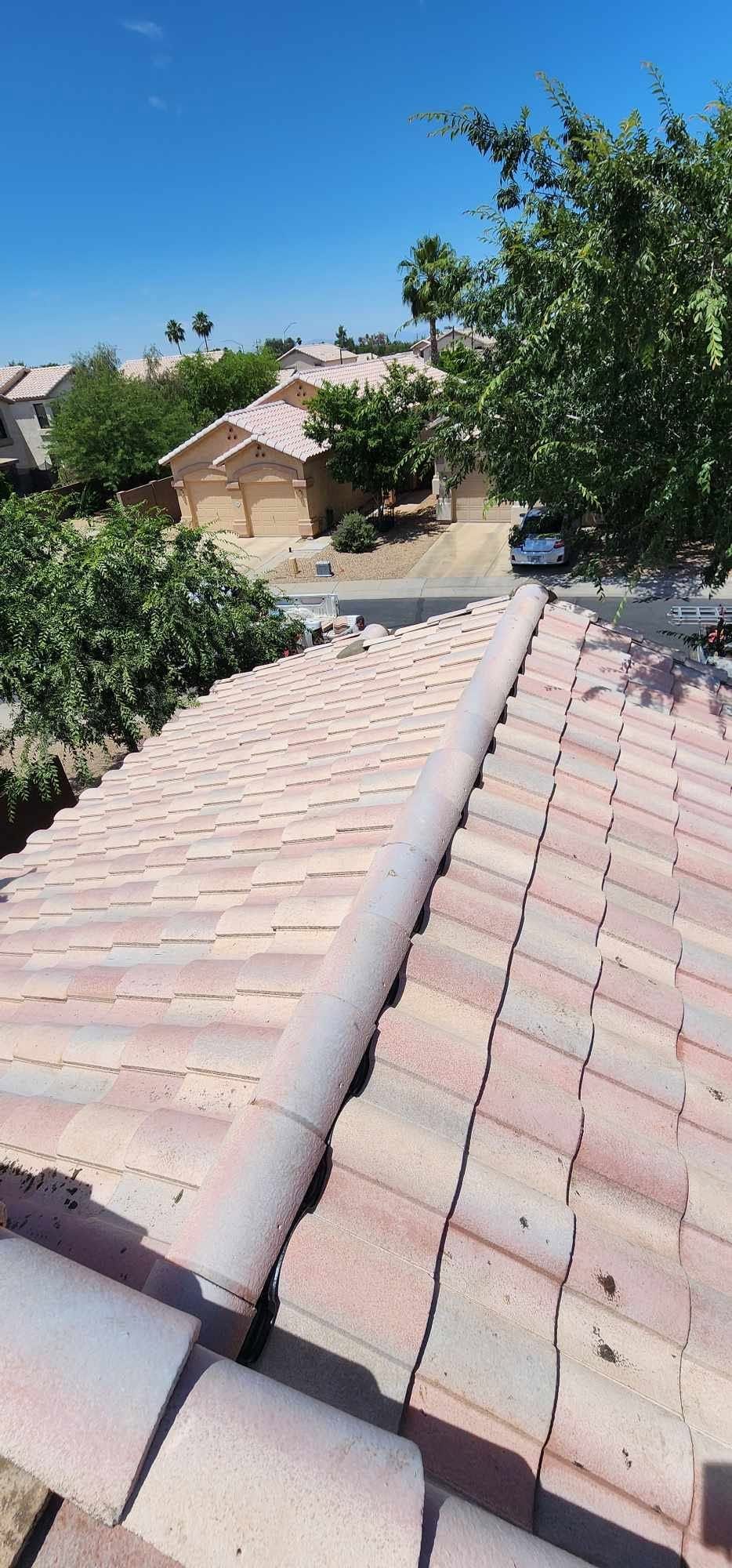 Rooftop with pink tile shingles overlooking trees and houses under a clear blue sky
