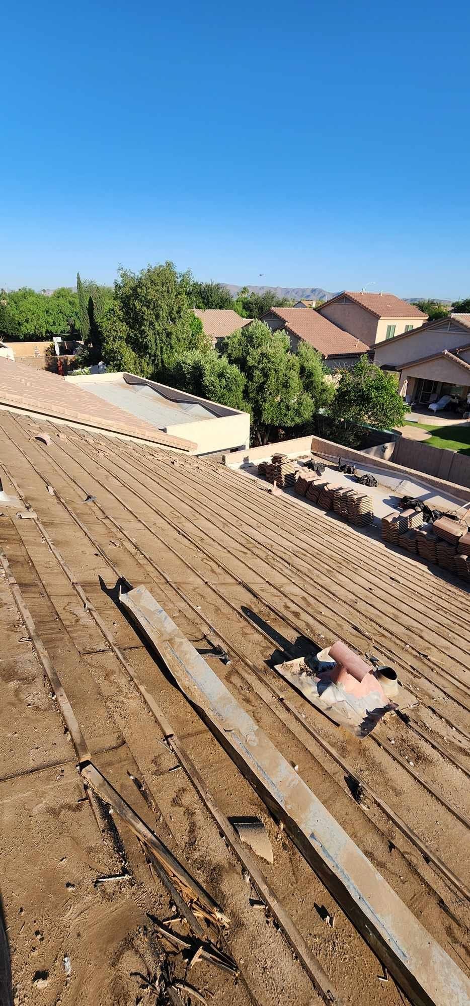 Rooftop under construction with plywood, lumber, and tools overlooking suburban houses and trees