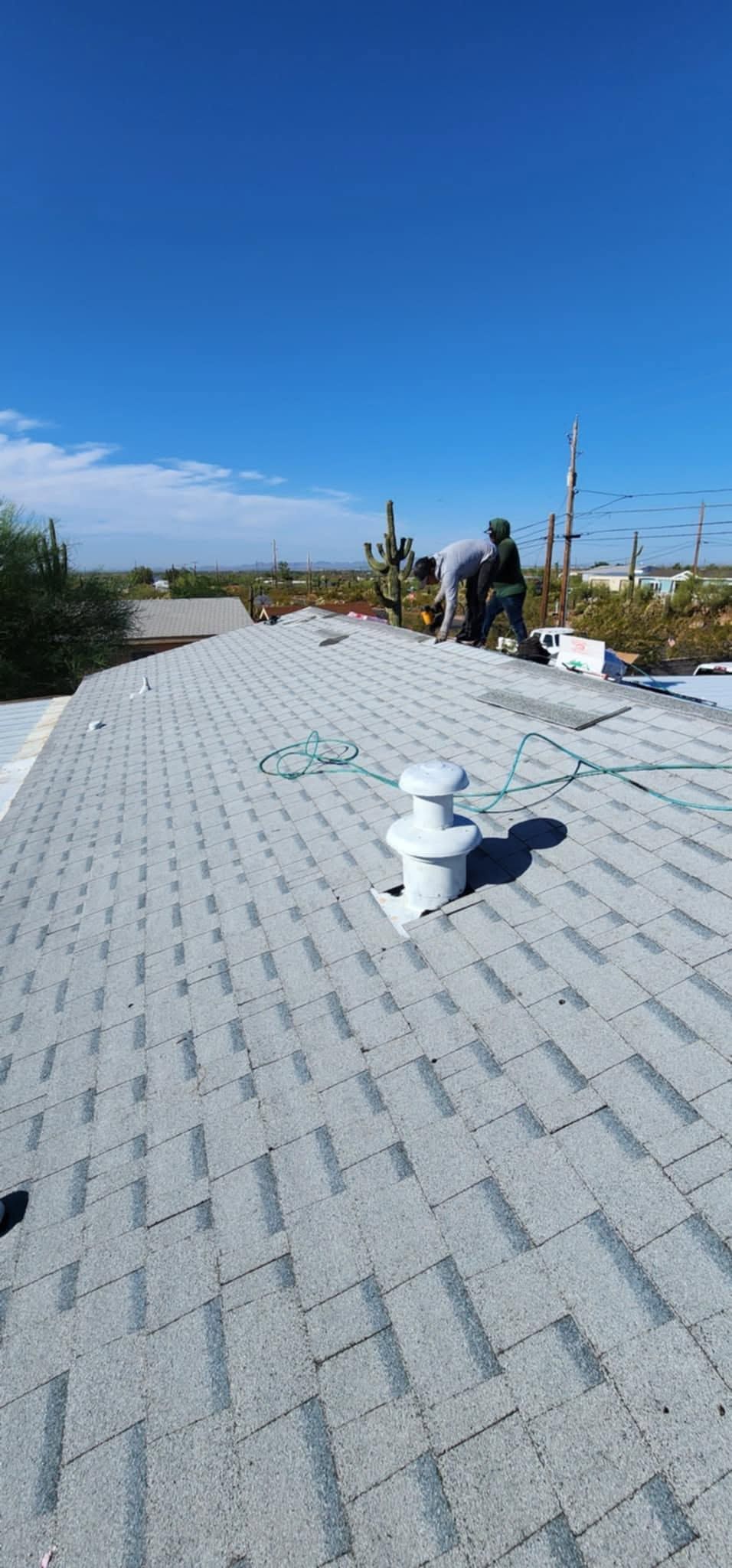 Rooftop with white gravel roof, vent pipes, and a person near the edge under a clear blue sky