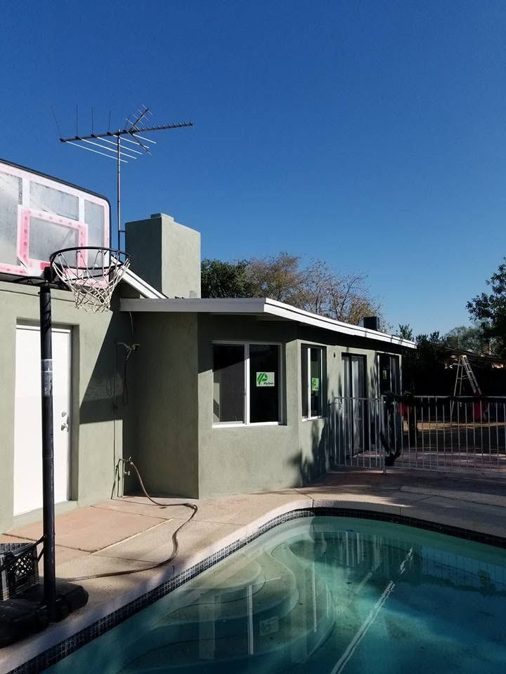 Backyard pool beside a house with a basketball hoop and antenna on the roof