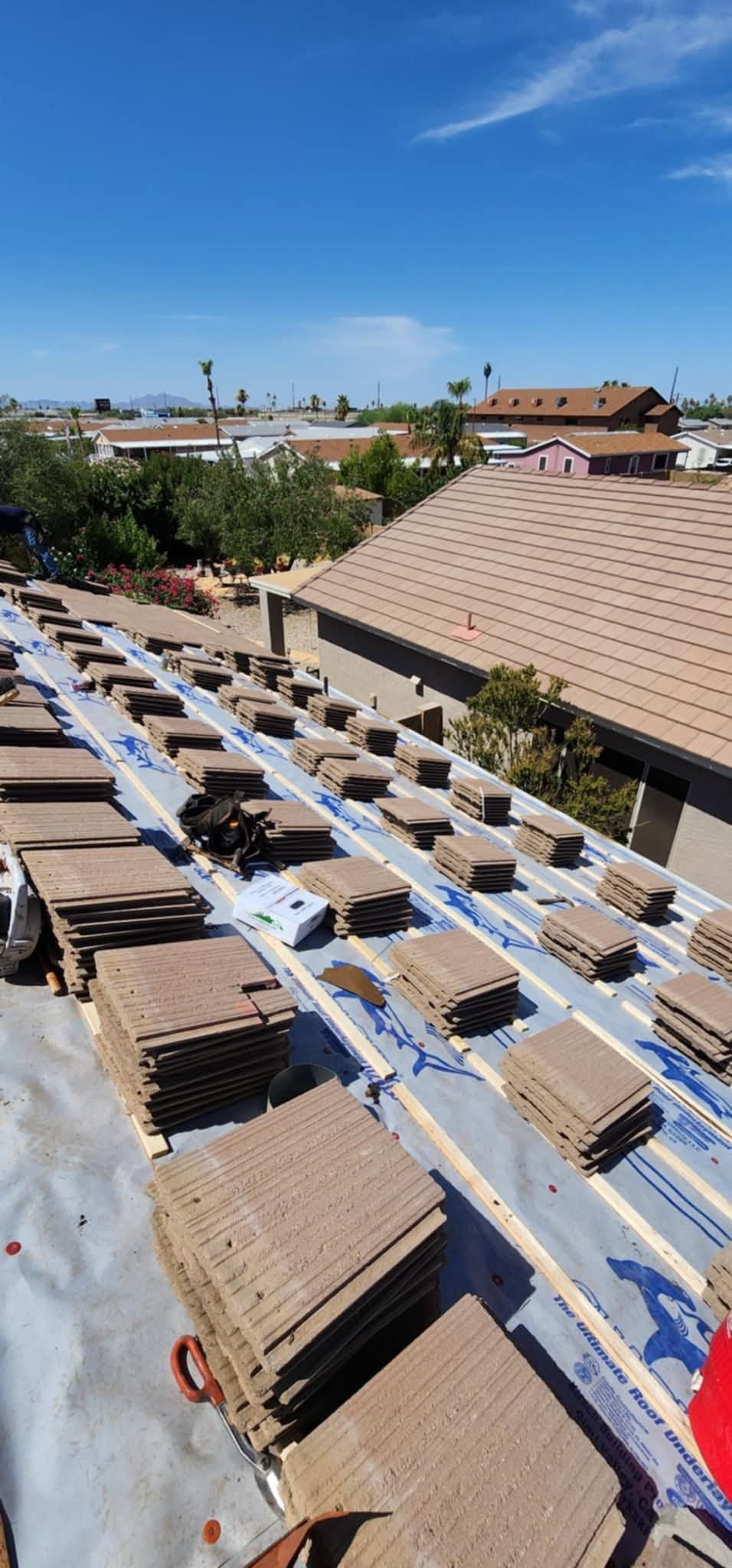 Rows of long tables under white canopies in a large outdoor courtyard, with buildings and blue sky in the background
