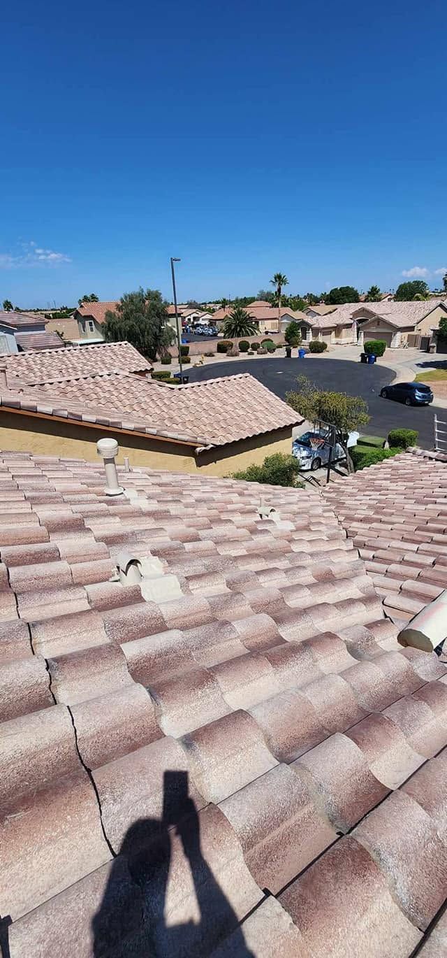 Rooftop view of a suburban neighborhood under a clear blue sky, with terracotta tiles in the foreground