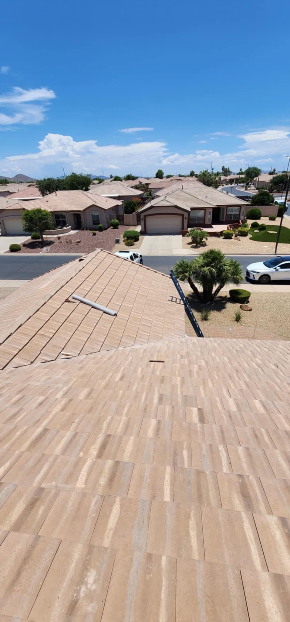 Rooftop view over a suburban neighborhood with tan houses and a blue sky
