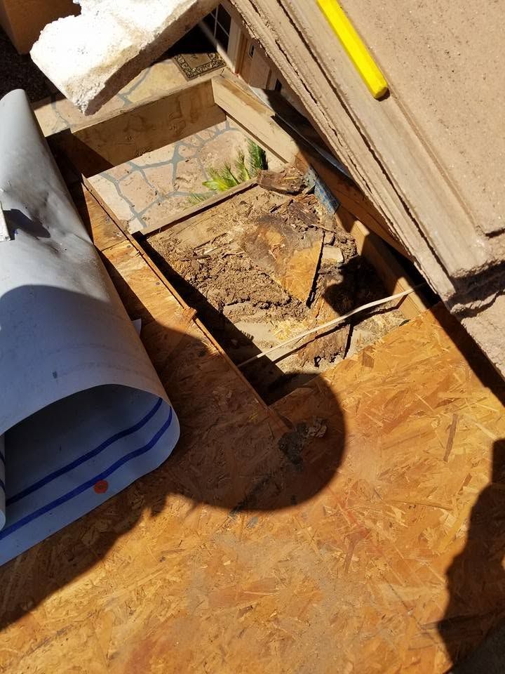 Damaged wooden floorboards with debris and a yellow tool on the right side.
