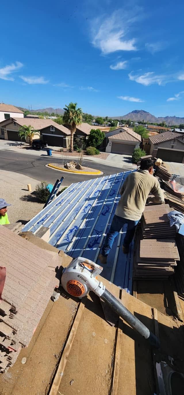Worker on a rooftop installing solar panels in a suburban neighborhood under a blue sky.
