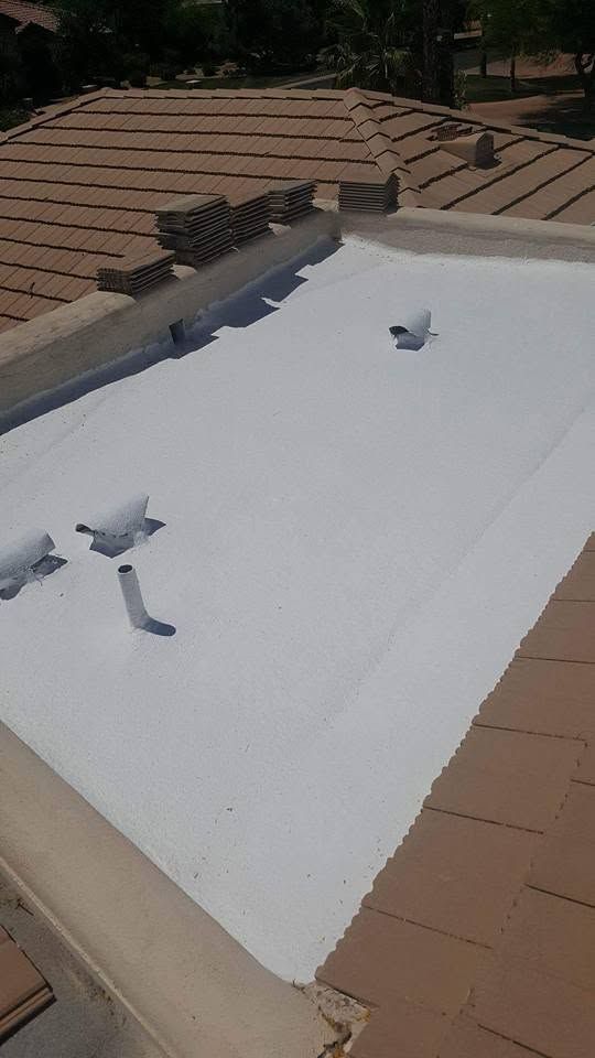 White roof membrane on a building under construction, with tan shingles around the edges and a rooftop vent.