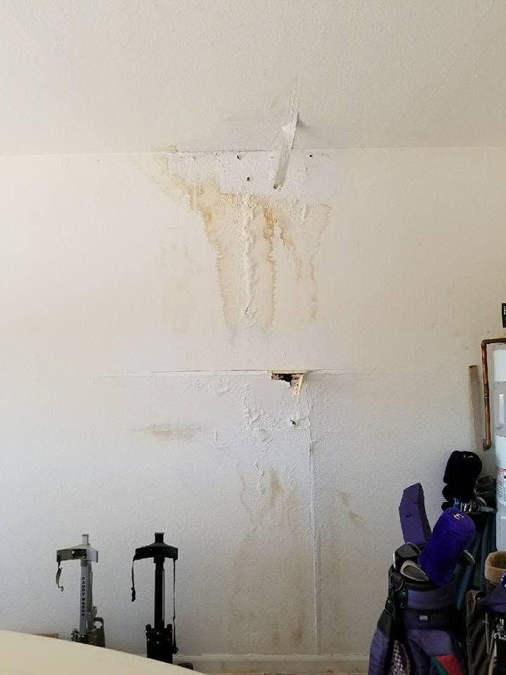 Wall with water stains and peeling paint above cleaning tools in a room