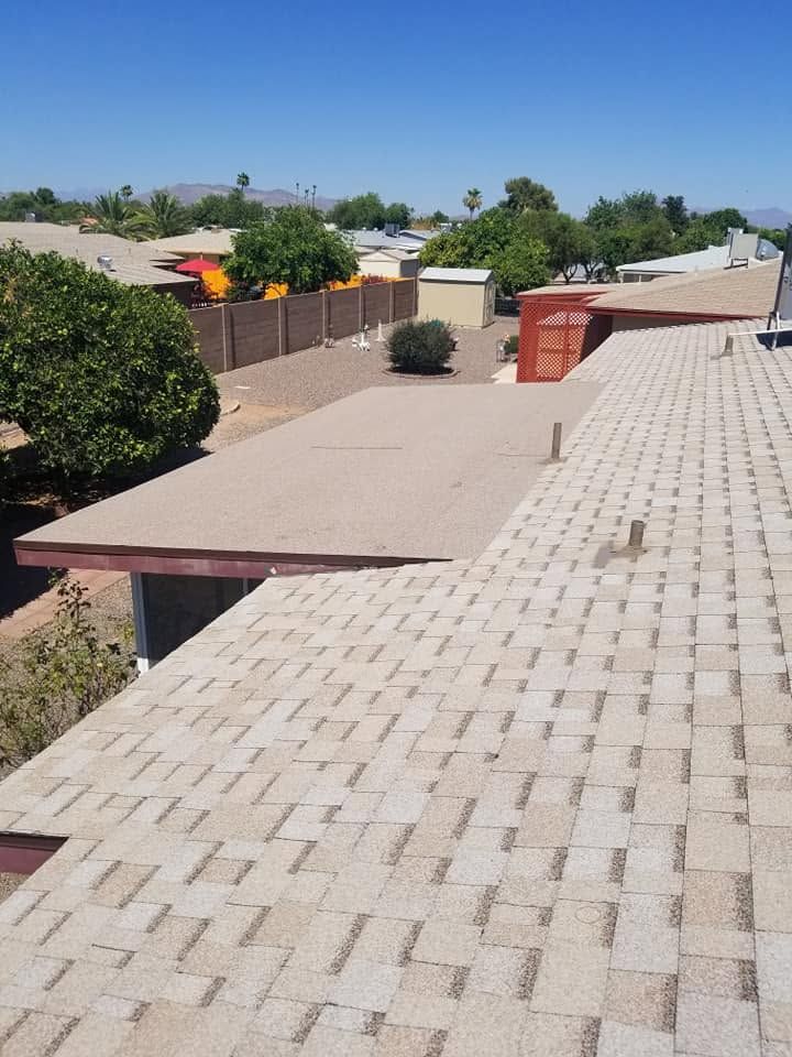 Rooftop walkway with tan pavers beside low walls and desert homes under a clear blue sky