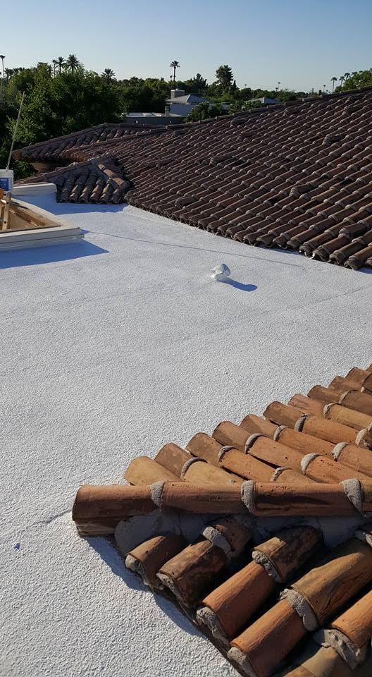 Flat rooftop with white coating, terracotta tiles, and a clear sky in the background