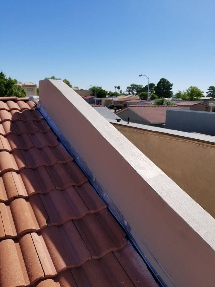 Rooftop with red clay tiles and a white stucco parapet wall under a clear blue sky