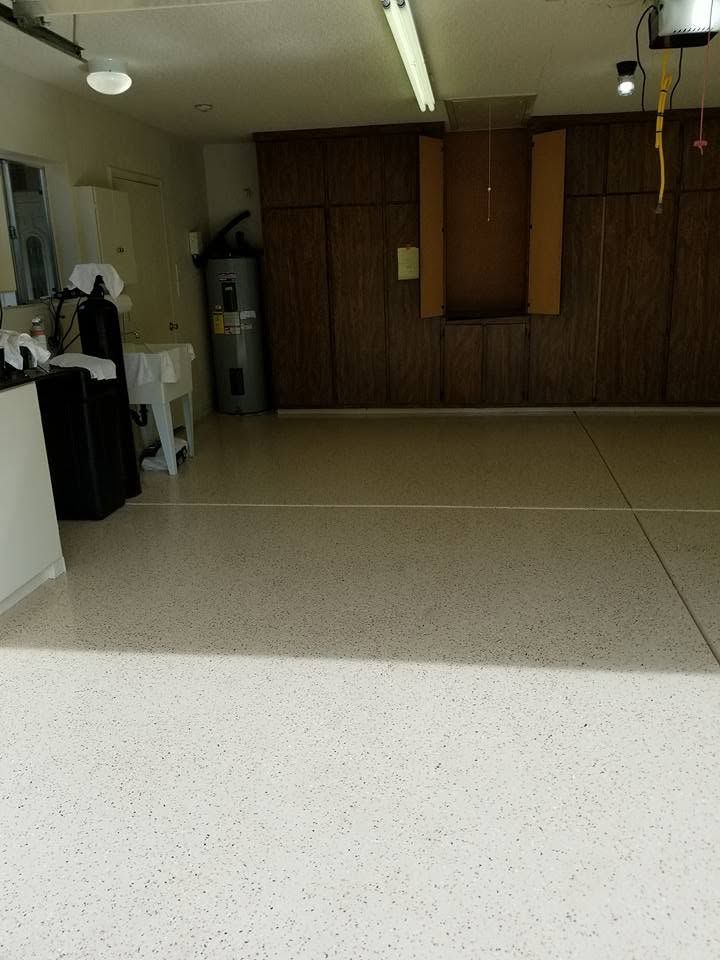 Empty room with speckled floor, wood-paneled wall, fluorescent lights, and cabinets in the back.