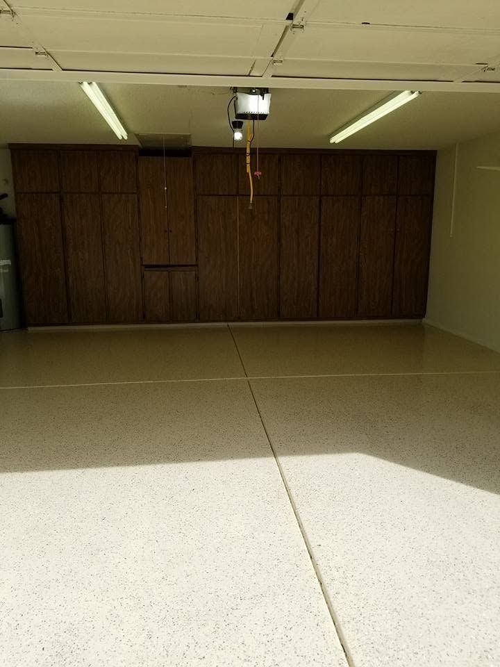 Empty indoor room with beige floor, wood-paneled wall, and ceiling lights above a projector.
