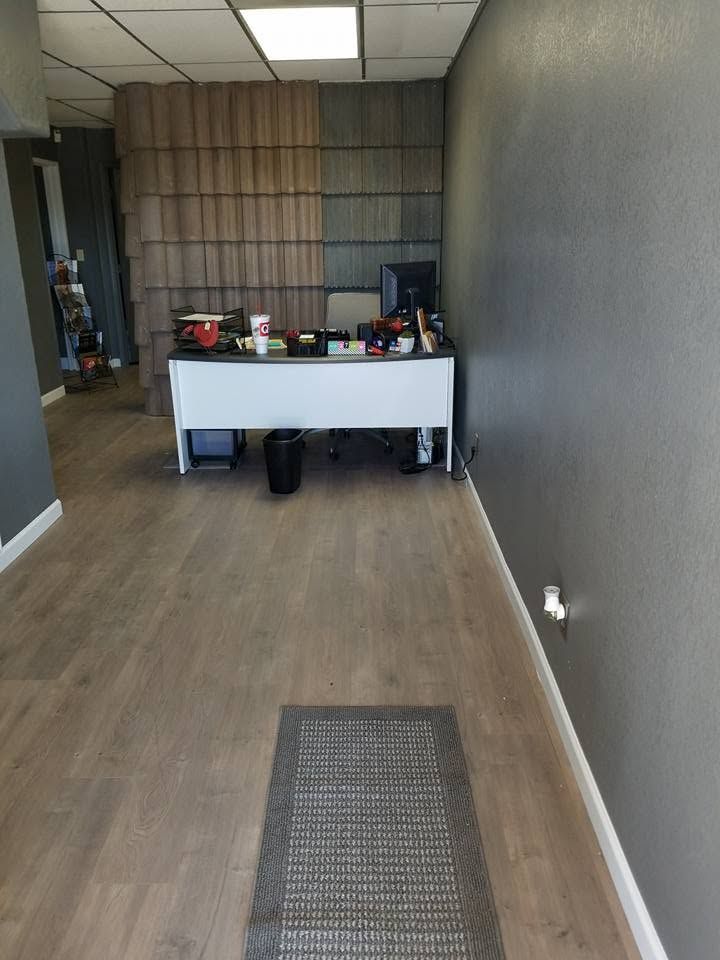 Empty hallway with a white desk at the far end and gray walls, wood floor, and a small rug.