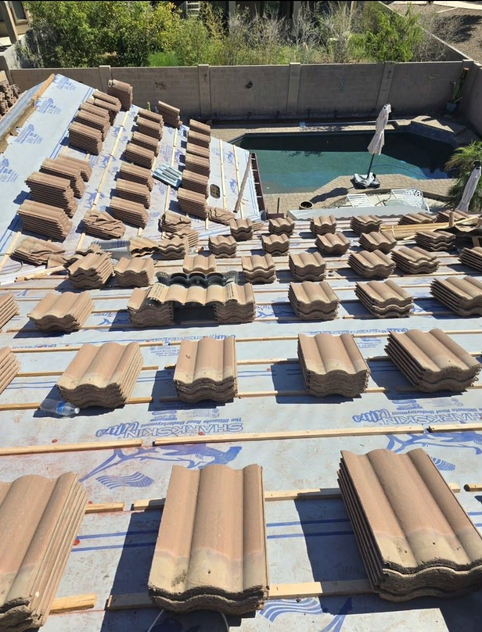 Rows of tan roof tiles laid out to dry on a blue tarp in a backyard beside a pool and fountain