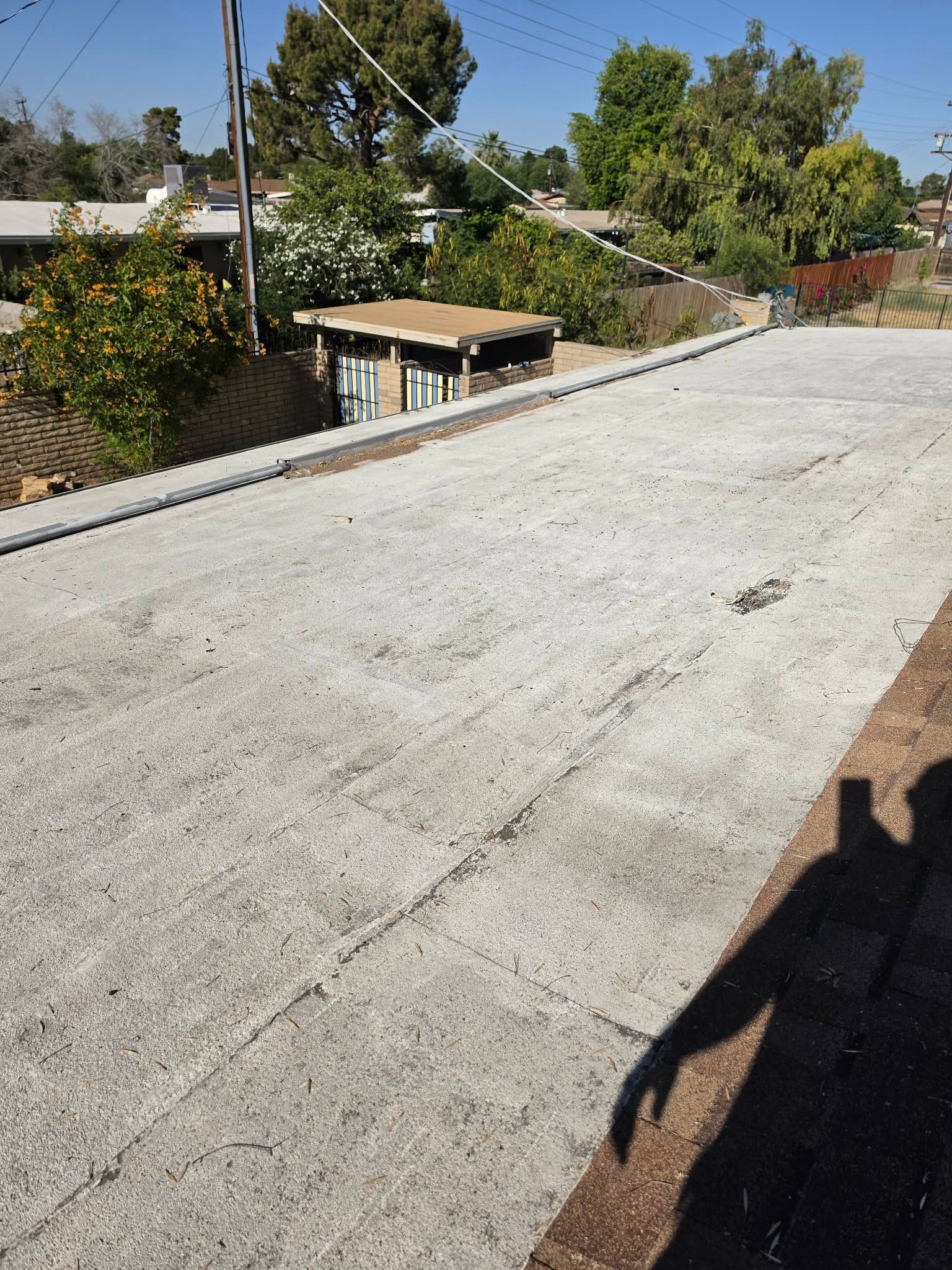 Steep concrete driveway beside hillside homes and trees under bright sunlight