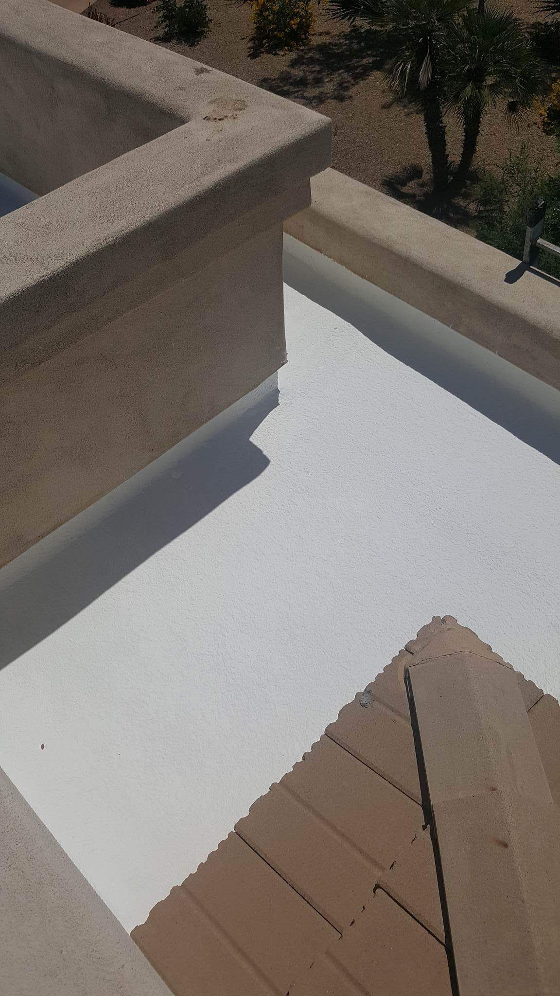 Sunlit rooftop patio with white floor, tan walls, and a wooden deck corner.