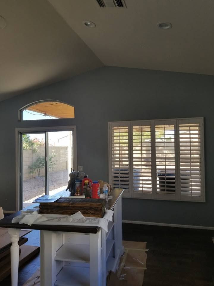 Sunlit kitchen under renovation with a worktable, tools, and shuttered windows.