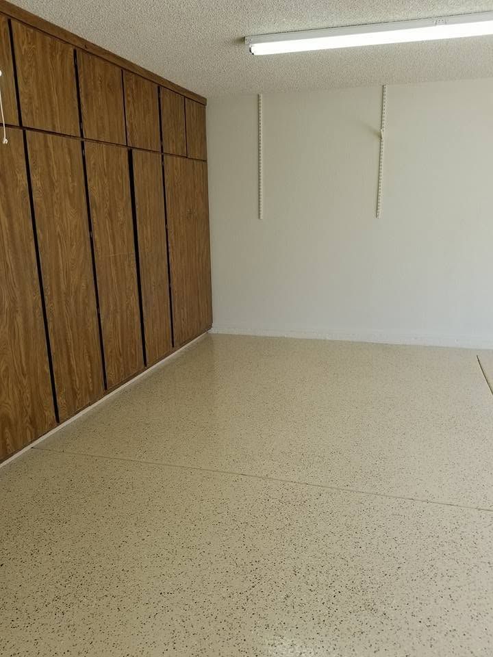 Empty room with wood-paneled closet doors, white walls, and beige speckled flooring.