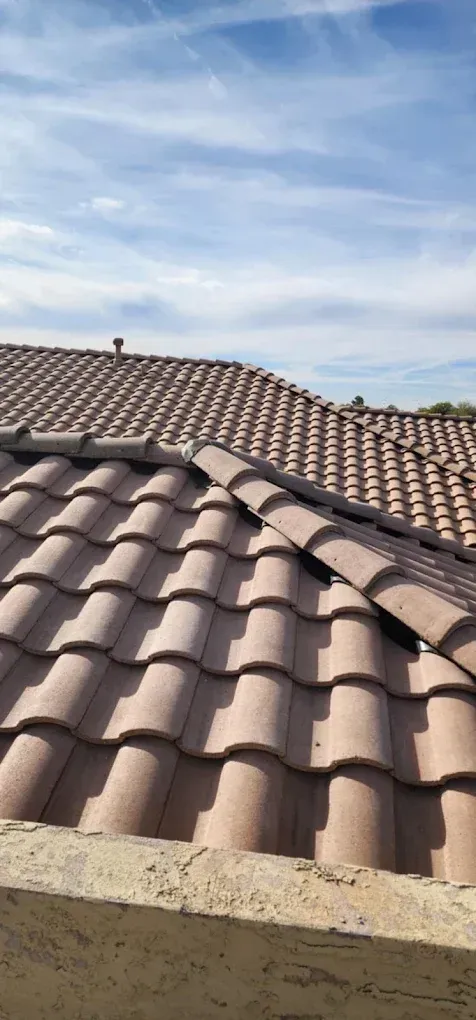 Tiled terracotta roof under a blue sky with wispy clouds