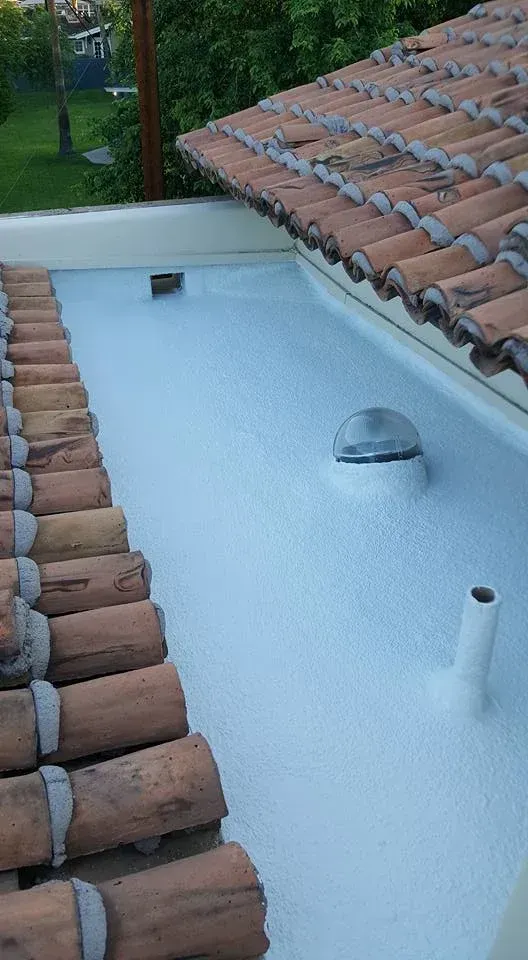 White rooftop water tank beside terracotta roof tiles and a vent pipe