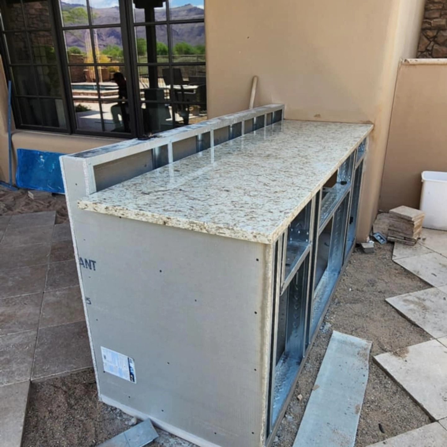 Outdoor HVAC cabinet with a speckled top beside a beige building and window