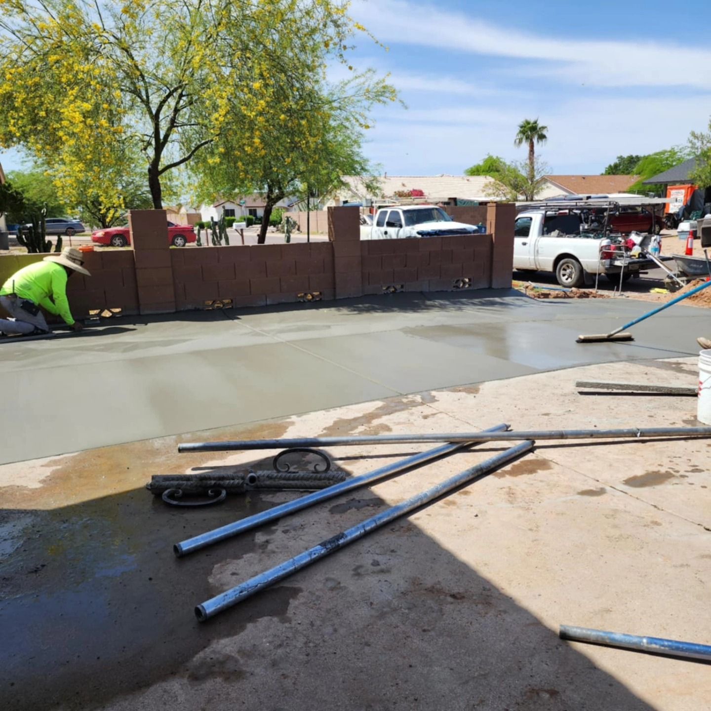 Fresh concrete being poured at a driveway or sidewalk repair site, with workers and equipment nearby