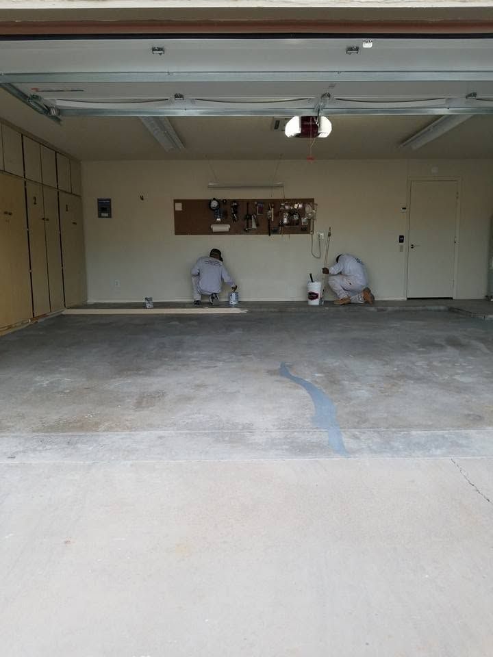 Partially open garage with two workers on the floor and tools near the back wall