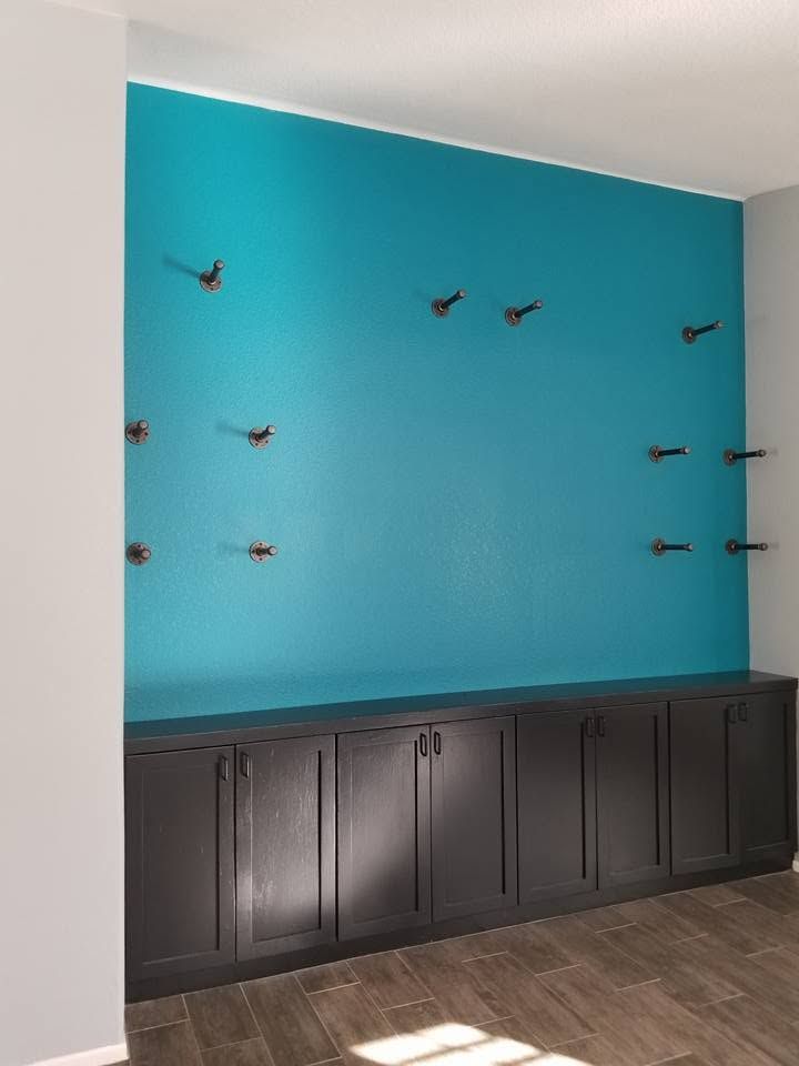 Teal accent wall with decorative bird mounts above dark cabinets in a modern room