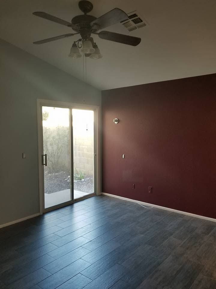 Empty room with dark tile floor, maroon accent wall, and sliding glass door to a patio.