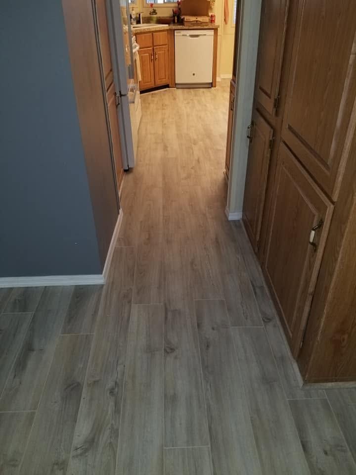 Hallway with light wood flooring leading to a kitchen and cabinets.