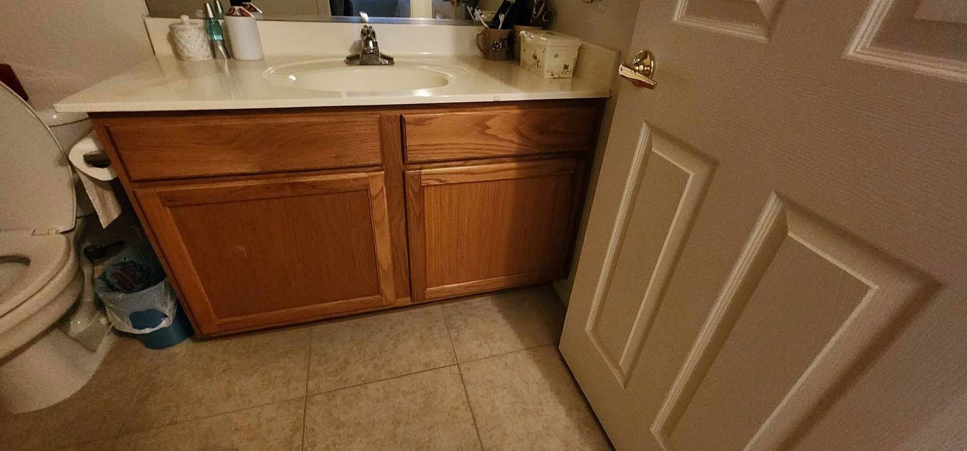 Small bathroom with a sink, wooden vanity, tiled floor, and a partially open door.
