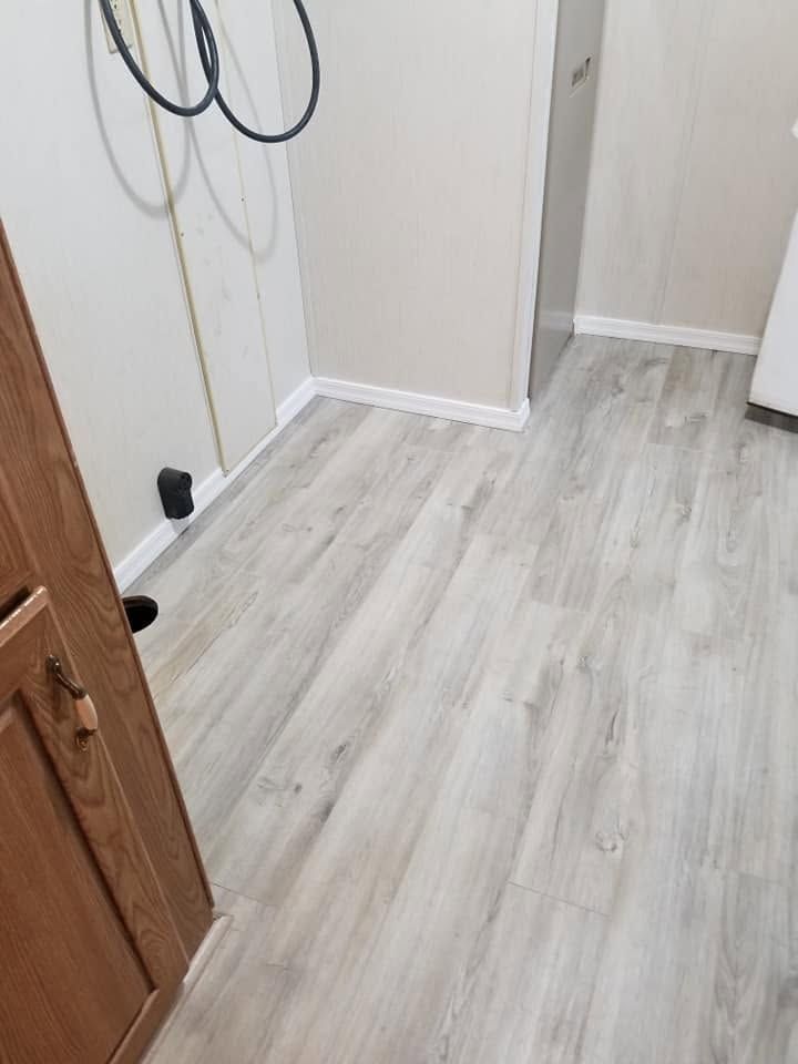 Small empty hallway with light wood flooring, white walls, and a partially open wooden door.