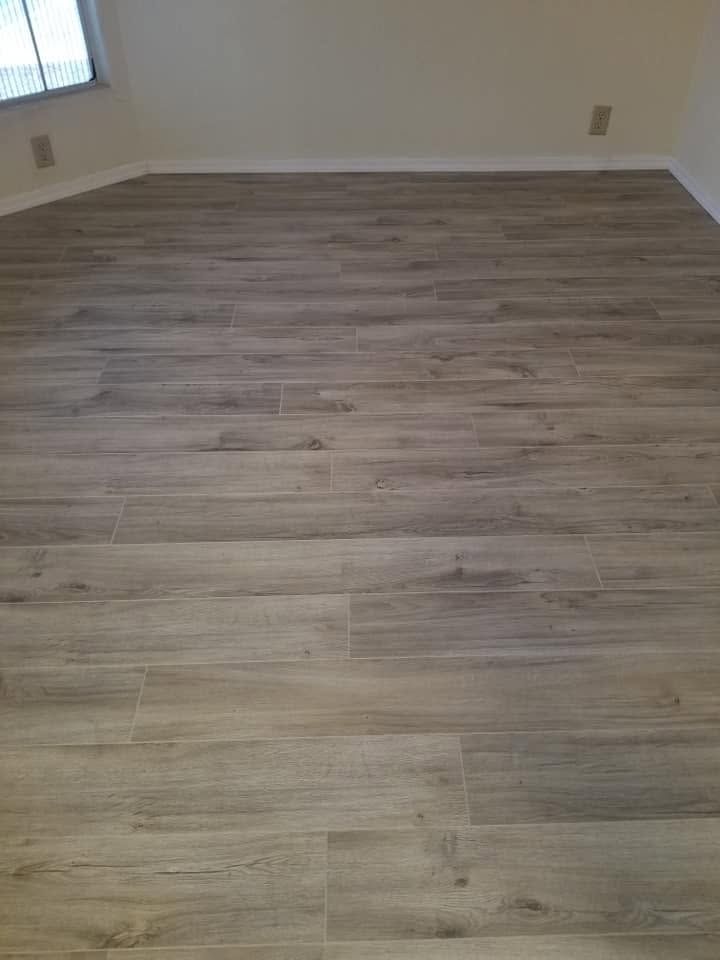 Empty room with light wood flooring, white walls, and a window on the left.
