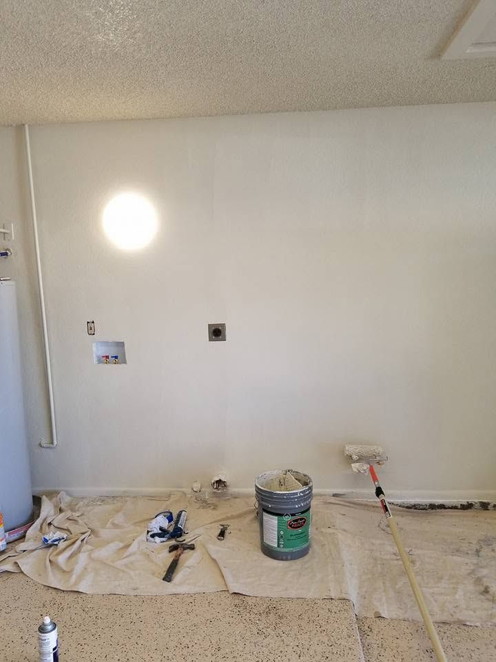Painted wall in a room with drop cloths, a bucket, and tools, mid-renovation.