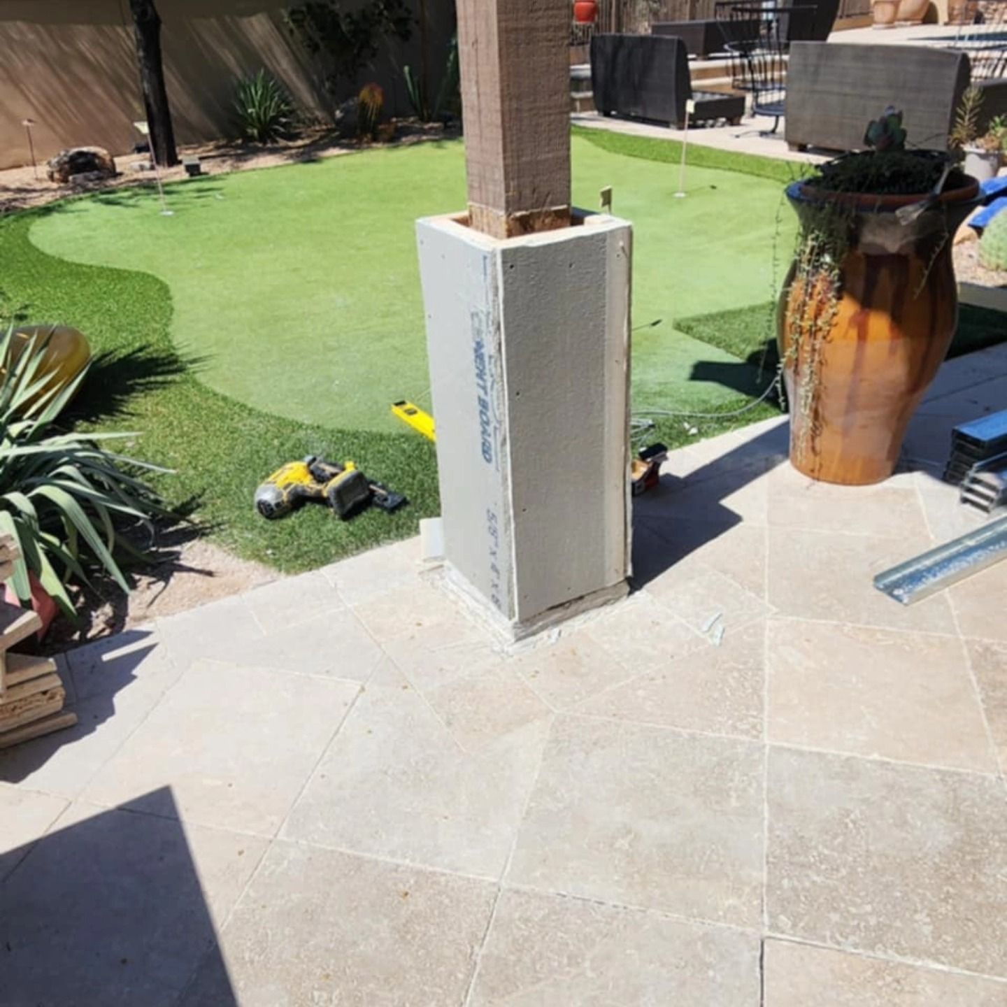 Patio with a white column, a toy truck on the grass, and a large planter on the right.