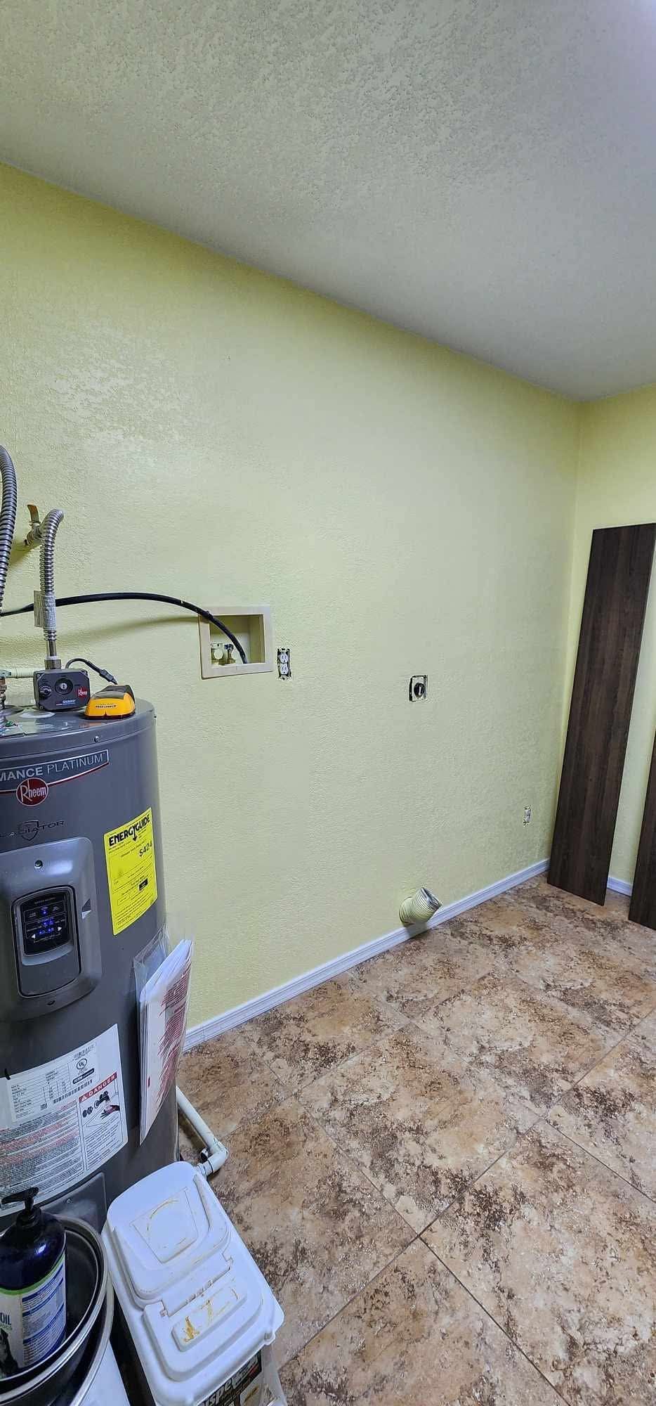 Small empty utility room with a water heater, beige walls, and a closed door.