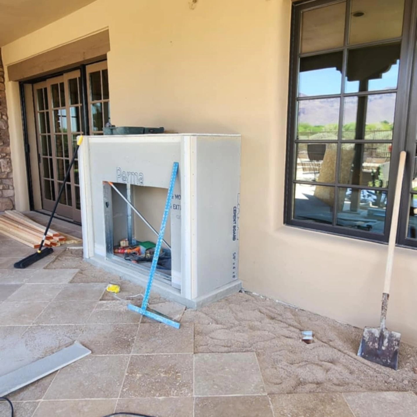 Patio with a large white cabinet being cleaned, blue broom leaning against it, and windows along the wall