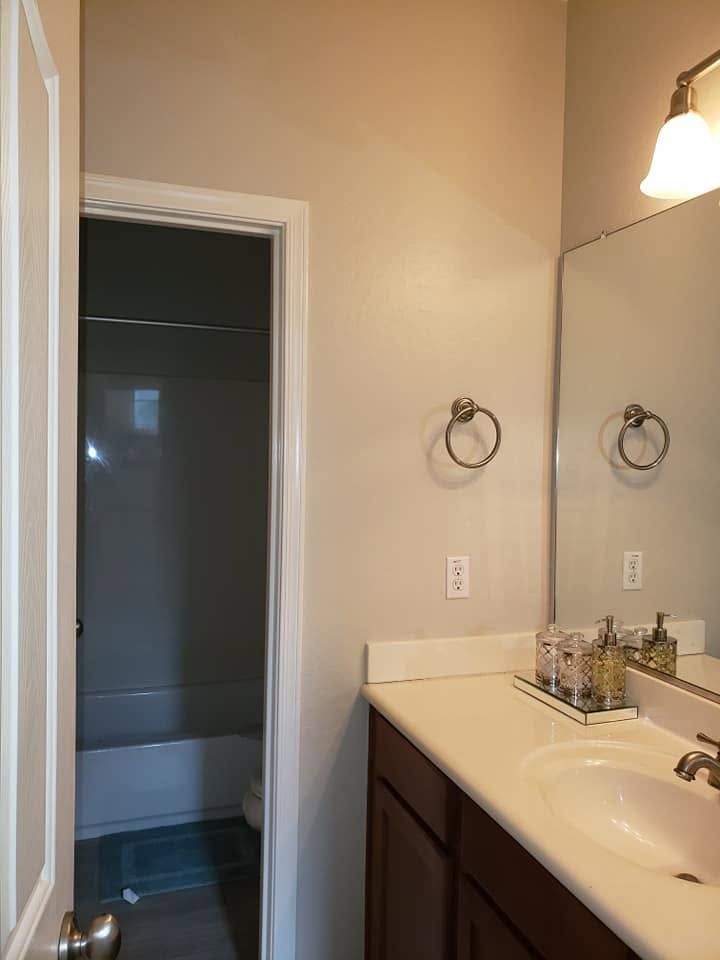 Bathroom vanity with sink and mirror beside an open doorway to a dark room
