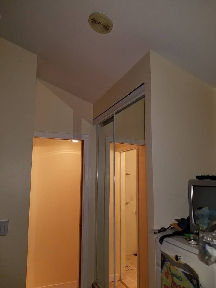 Hallway with an open door, mirrored closet, and warm light spilling from a room.