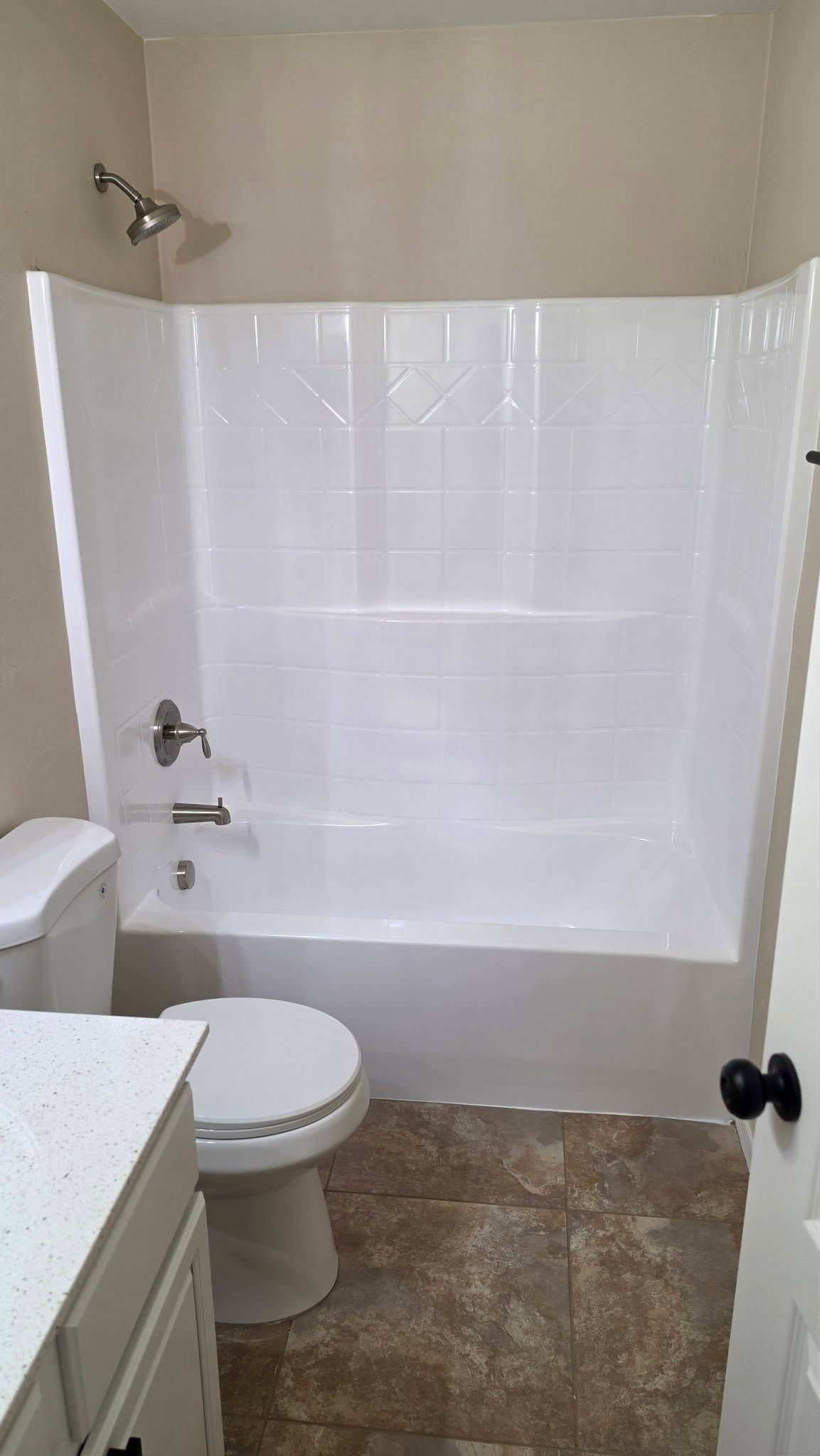 Bathroom with a white shower curtain, toilet, and vanity with speckled stone floor.