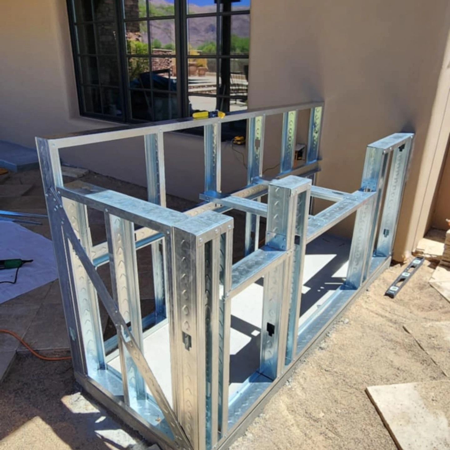 Galvanized steel frame structure under construction beside a building wall and window