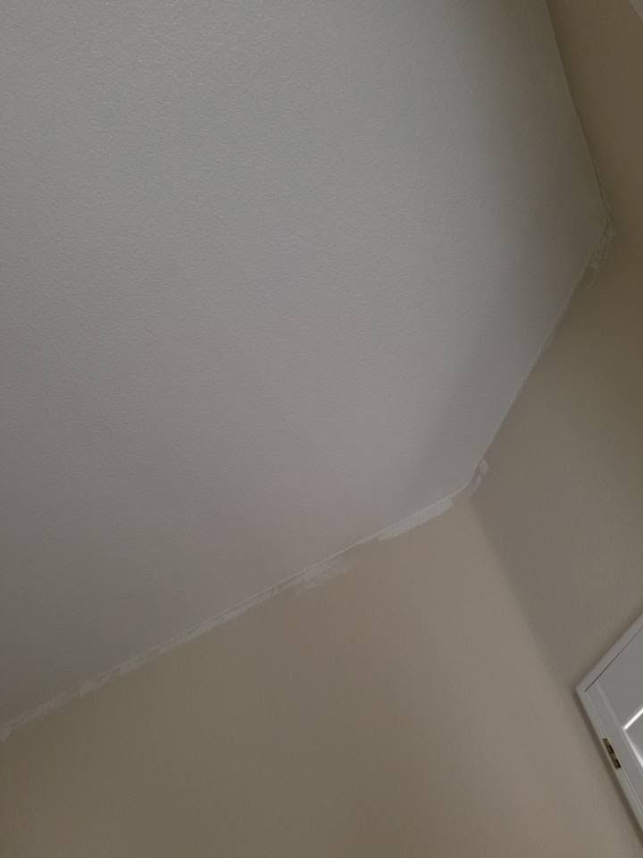 Corner of a beige room with a white ceiling and part of a light switch visible