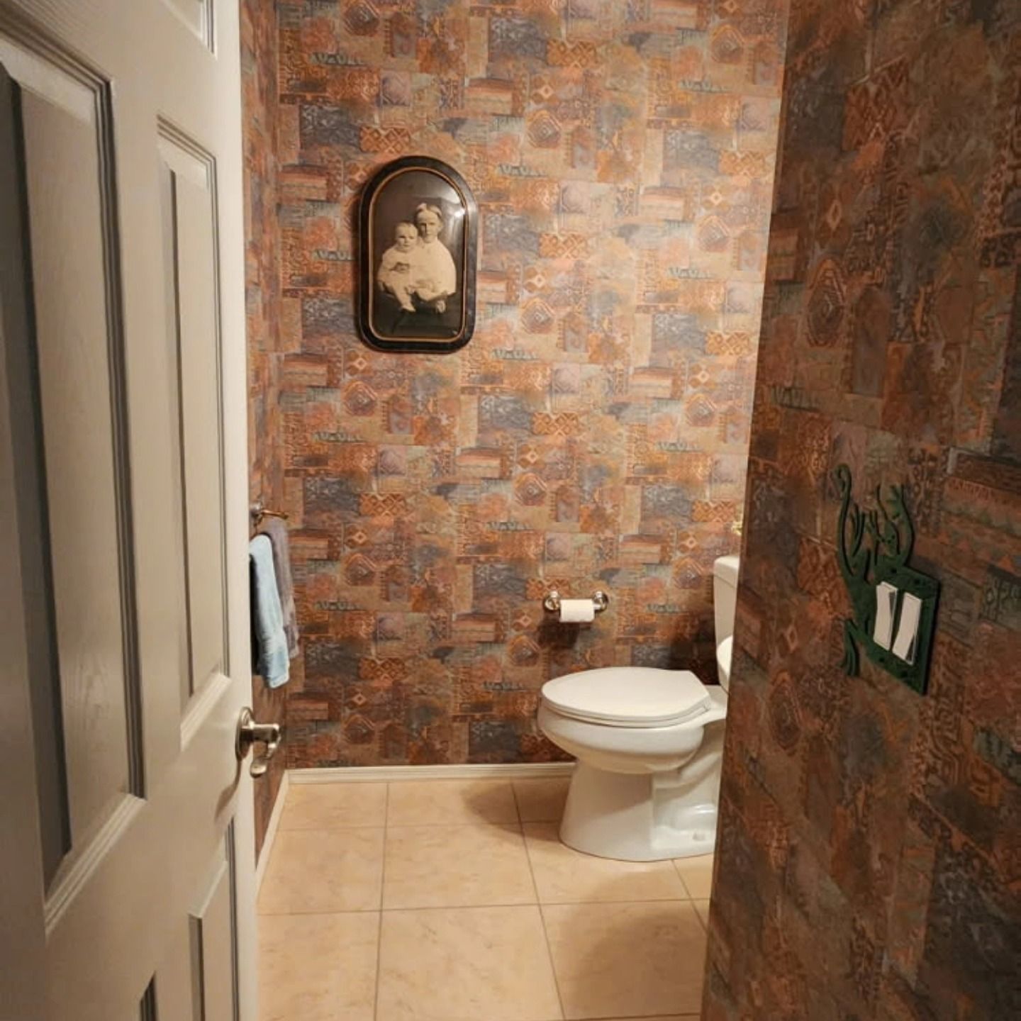 Small bathroom with beige tile, stone-pattern walls, a toilet, and an arched wall decoration.