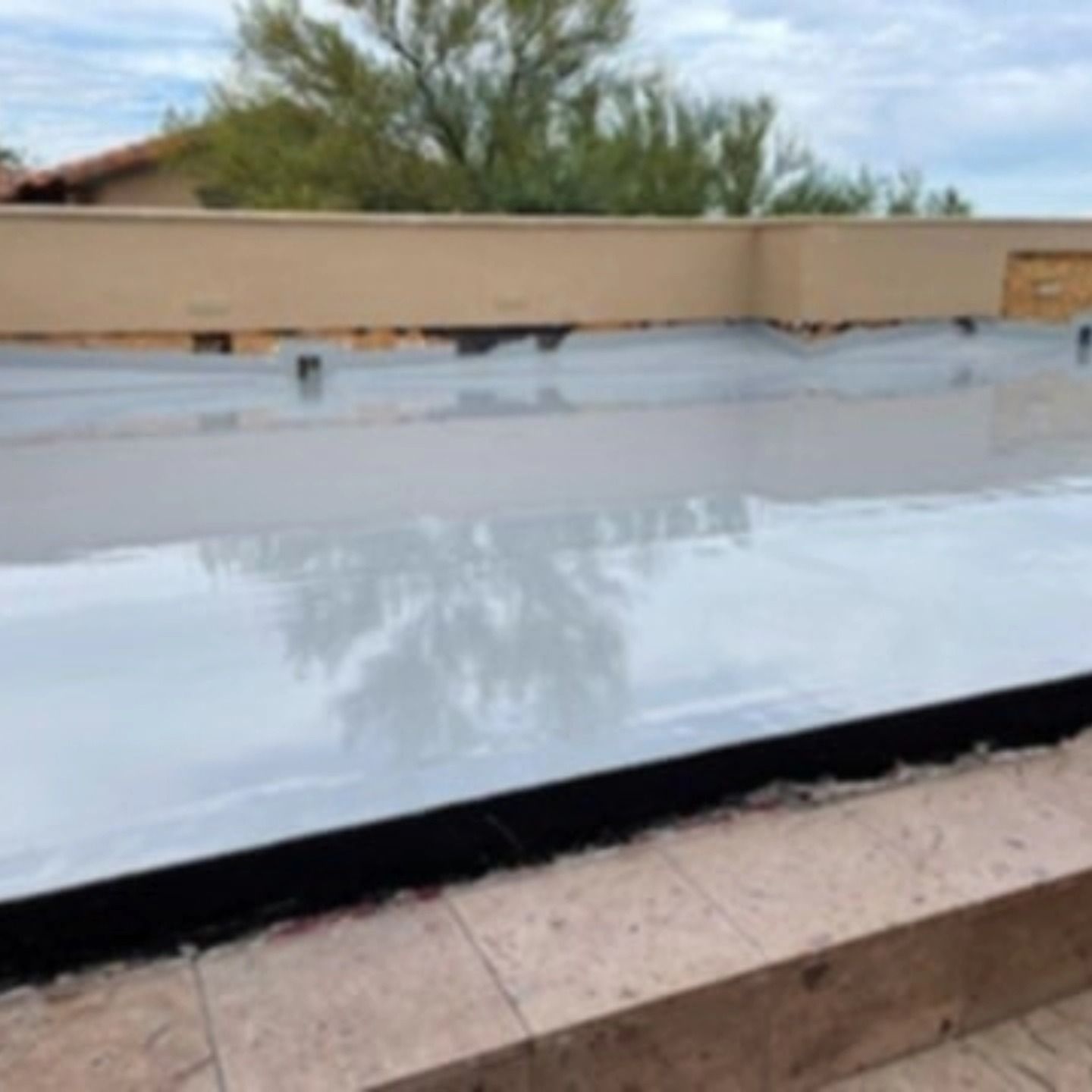 Rooftop with a large reflective white sheet or membrane stretched across it under a cloudy sky.